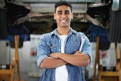Buy stock photo Portrait of a handsome young mechanic standing with his arms folded in his workshop