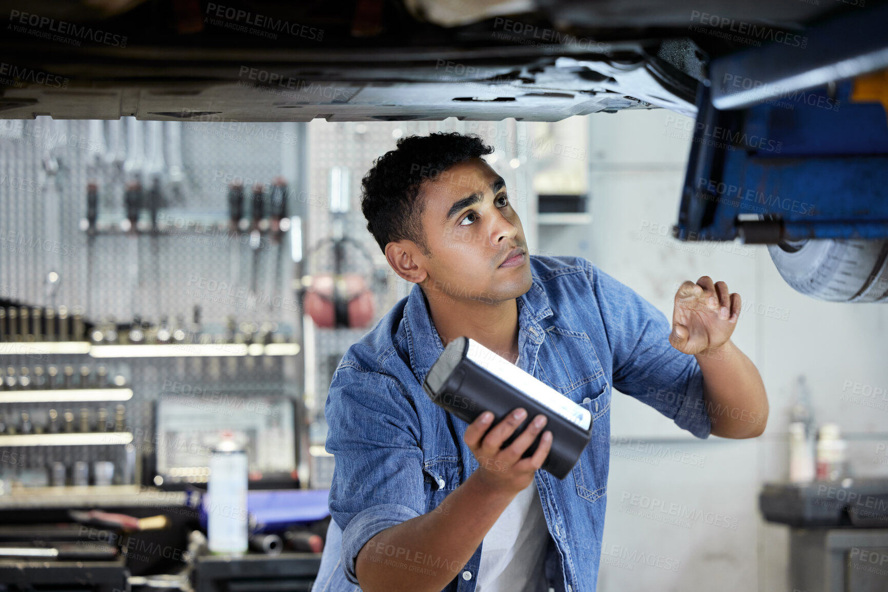 Buy stock photo Man, mechanic and bottom of car in workshop for working or maintenance, inspection and oil change with light. Person, motor and garage for engine or exhaust diagnostics, transmission and brake repair
