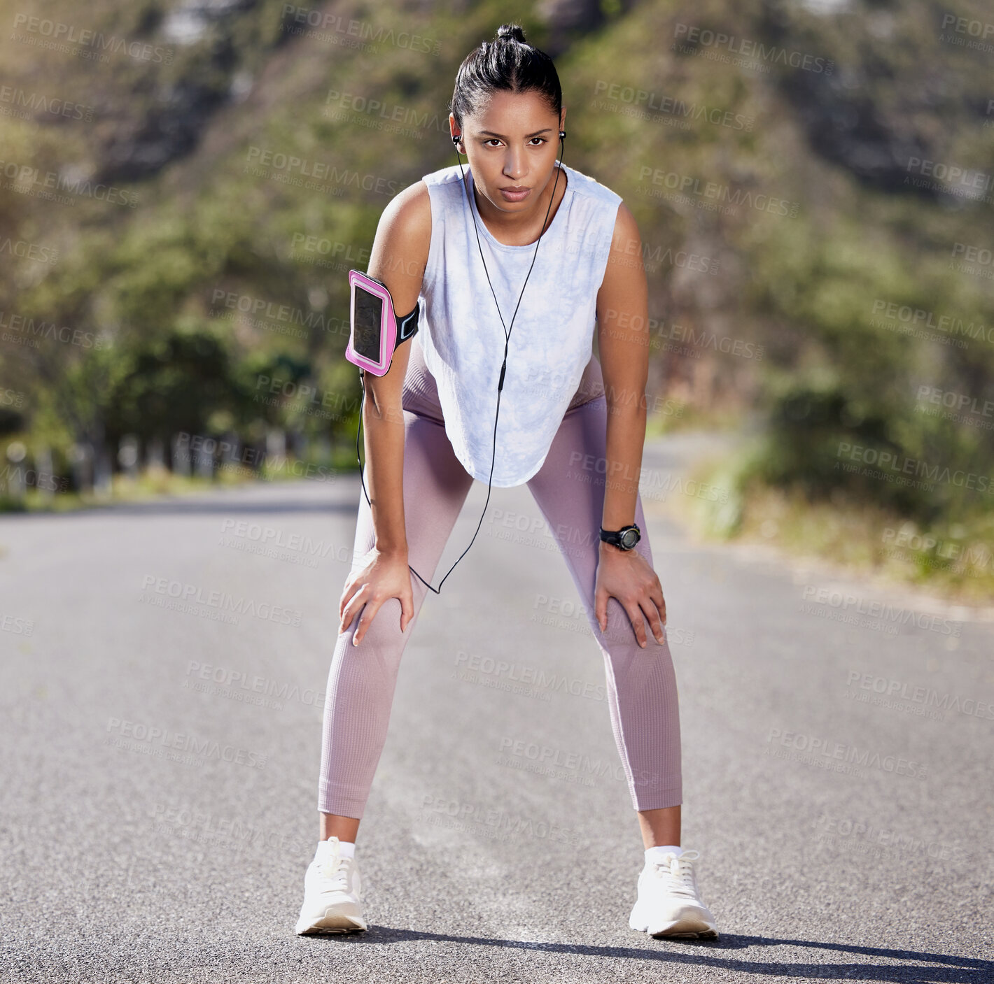 Buy stock photo Full length shot of an attractive young female athlete looking tired during a run outside