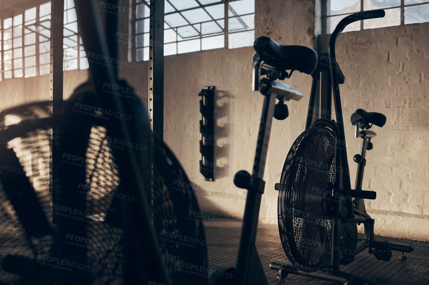 Buy stock photo Spinning bike, empty and gym for exercise with a shadow background at a warehouse with light. Club, cardio bicycle for fitness equipment for training and workout in storage venue in the dark.