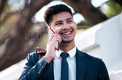 Buy stock photo Shot of a young businessman talking on a cellphone while out in the city