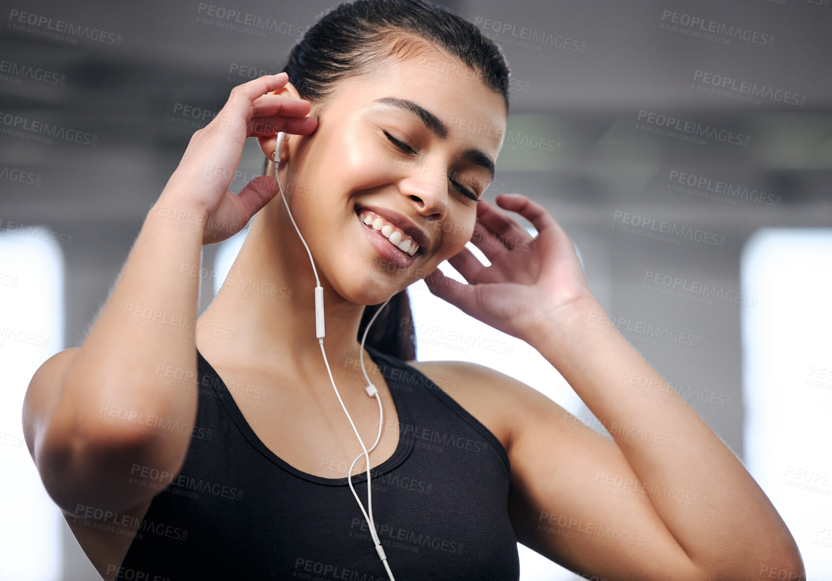 Buy stock photo Shot of a fit young woman using earphones at the gym