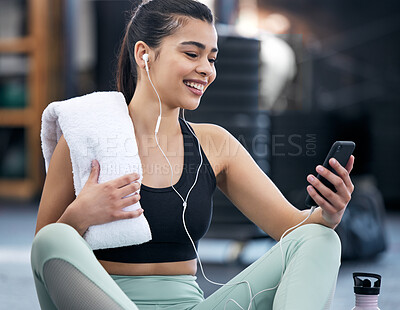 Buy stock photo Earphones, gym and woman with phone, watch and video of fitness, exercise and online for wellness. Technology, mobile and social media for happiness, person and athlete on break, relax and towel
