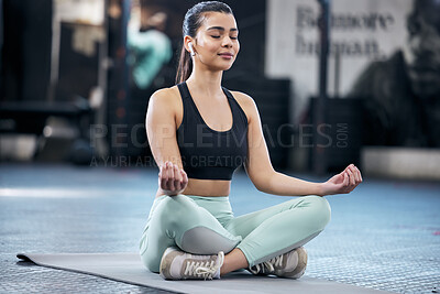 Buy stock photo Shot of a fit young woman meditating at a gym