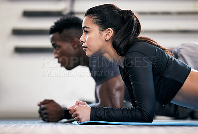 Buy stock photo Shot of a young man and woman doing plank exercises in a gym