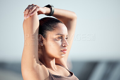 Buy stock photo Shot of a sporty young woman stretching her arms while exercising outdoors