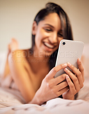 Buy stock photo Shot of a young woman using her cellphone while lying topless on her bed