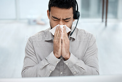 Buy stock photo Shot of a young businessman blowing his nose while working in a call centre