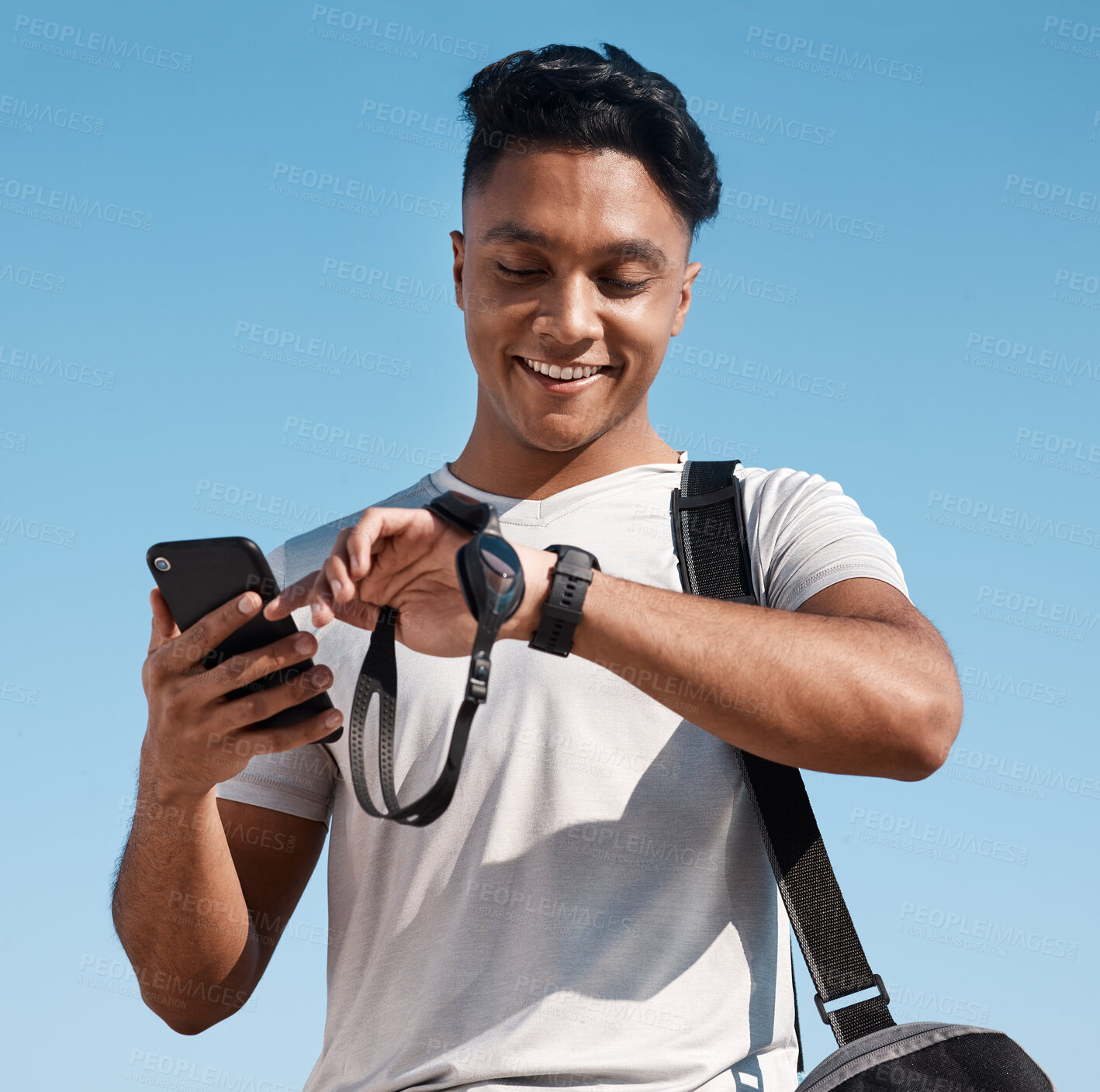 Buy stock photo Shot of a young man looking at his watch before going for a swim