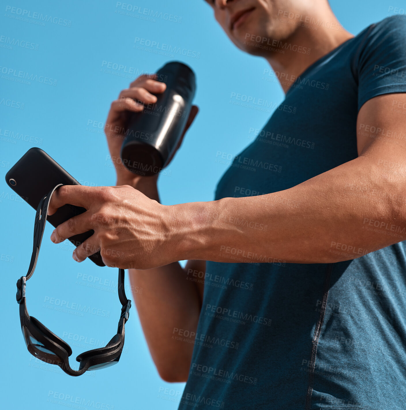 Buy stock photo Shot of an unrecognisable man using a smartphone before going for a swim