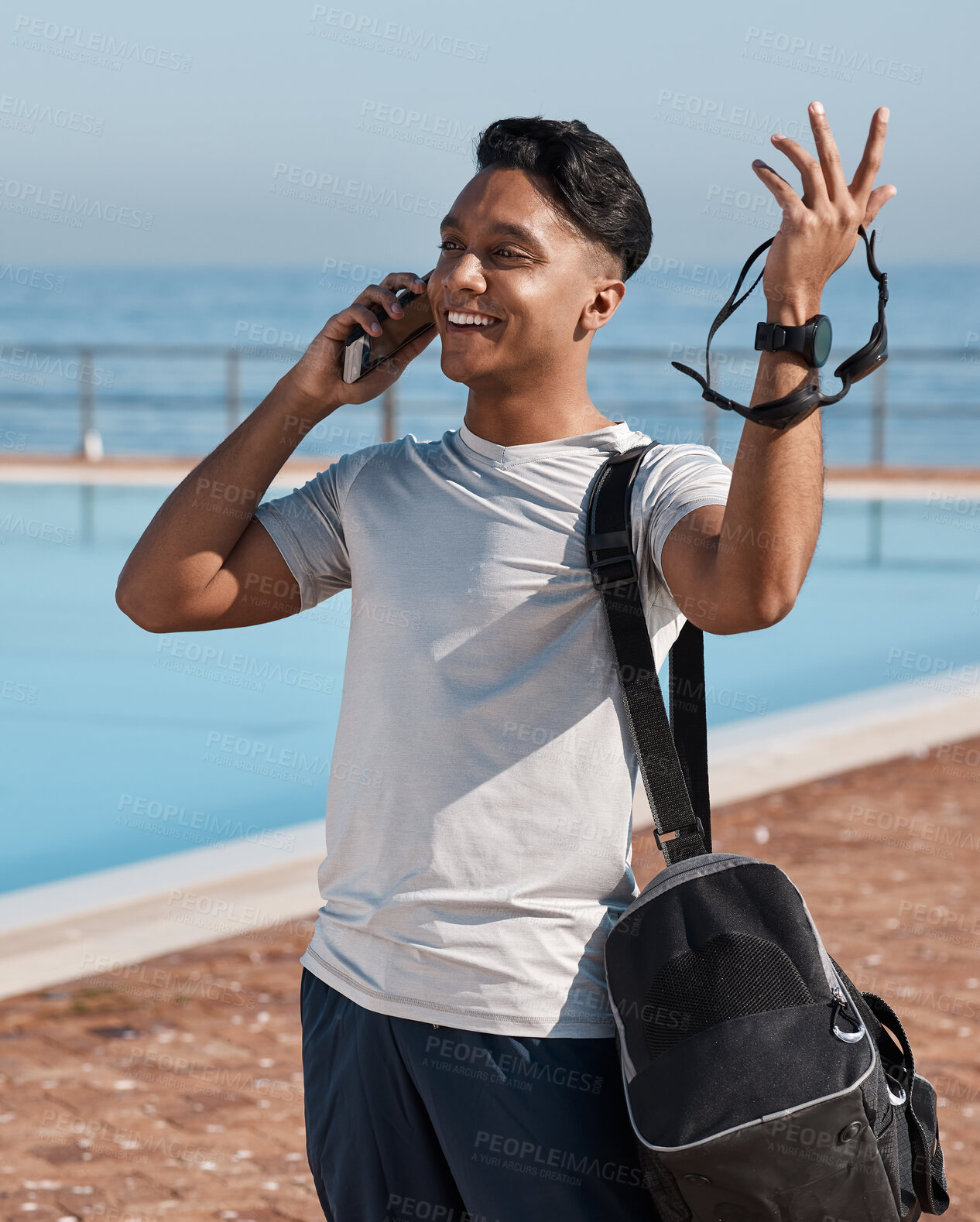 Buy stock photo Shot of a young man using a smartphone before going for a swim