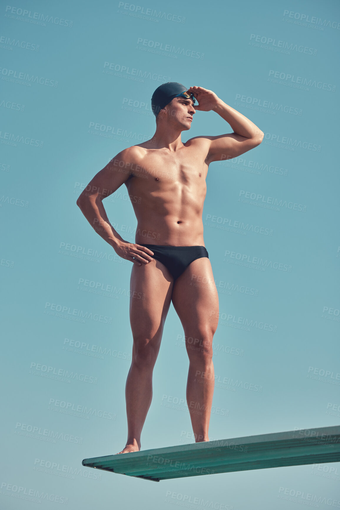 Buy stock photo Full length shot of a handsome young male athlete standing on a diving board outside