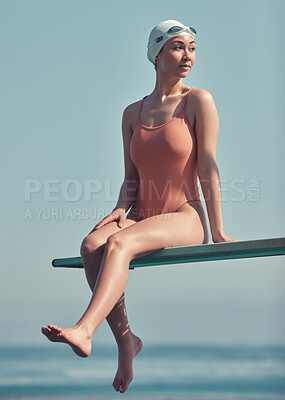 Buy stock photo Full length shot of an attractive young female athlete sitting on a diving board outside