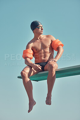 Buy stock photo Full length shot of a handsome young male athlete sitting on a diving board outside