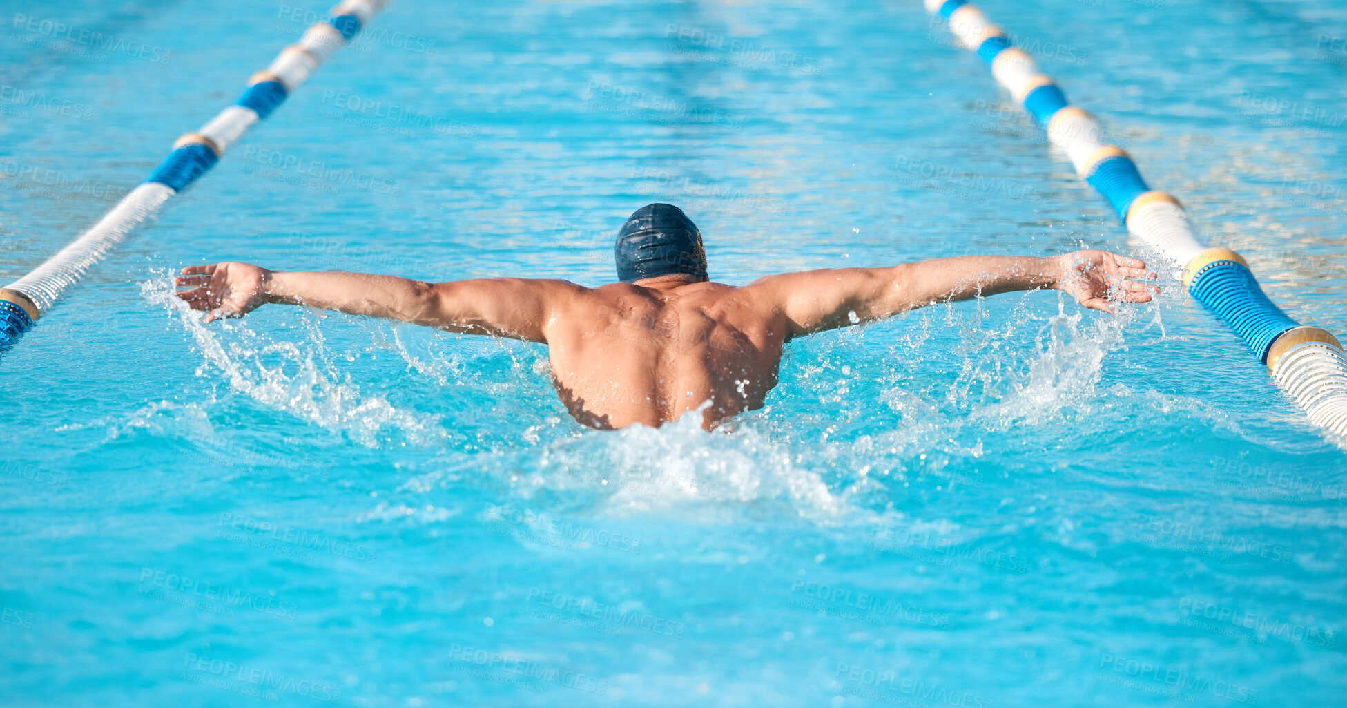 Buy stock photo Shot of an unrecognizable young male athlete swimming in an olympic-sized pool