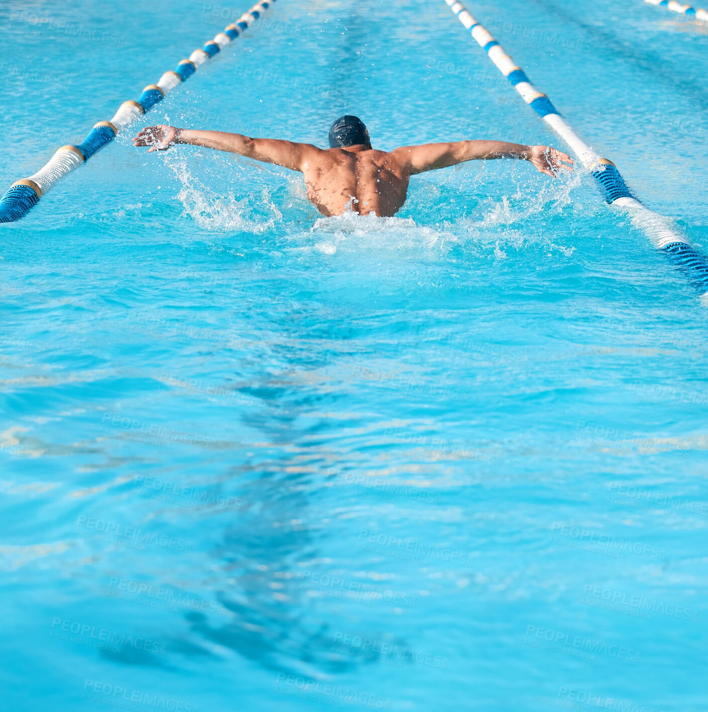 Buy stock photo Shot of an unrecognizable young male athlete swimming in an olympic-sized pool