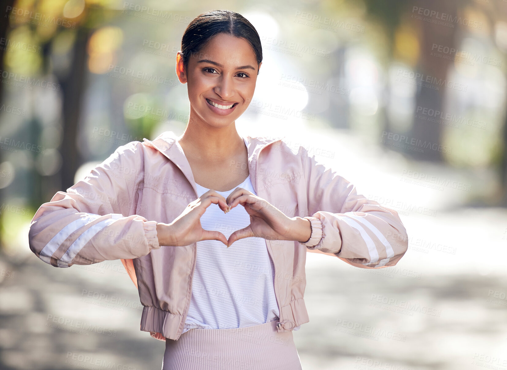 Buy stock photo Girl, portrait and outdoor for fitness, heart and sportswear in nature, smile and exercise on road. Wellness, city and runner with happiness, hands and gesture of love, healthy and bokeh in park