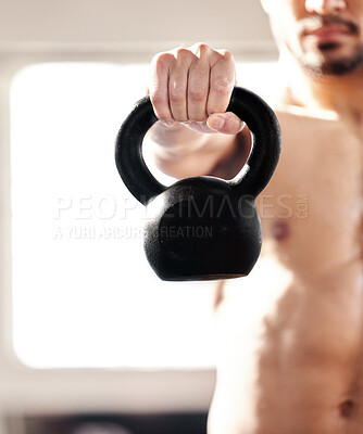 Buy stock photo Cropped shot of a young man working out with a kettle bell in a gym