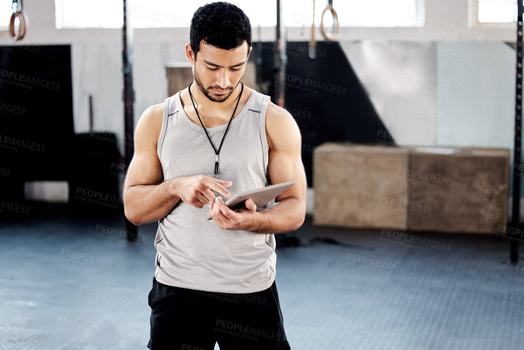 Buy stock photo Shot of a handsome young man using a digital tablet at the gym