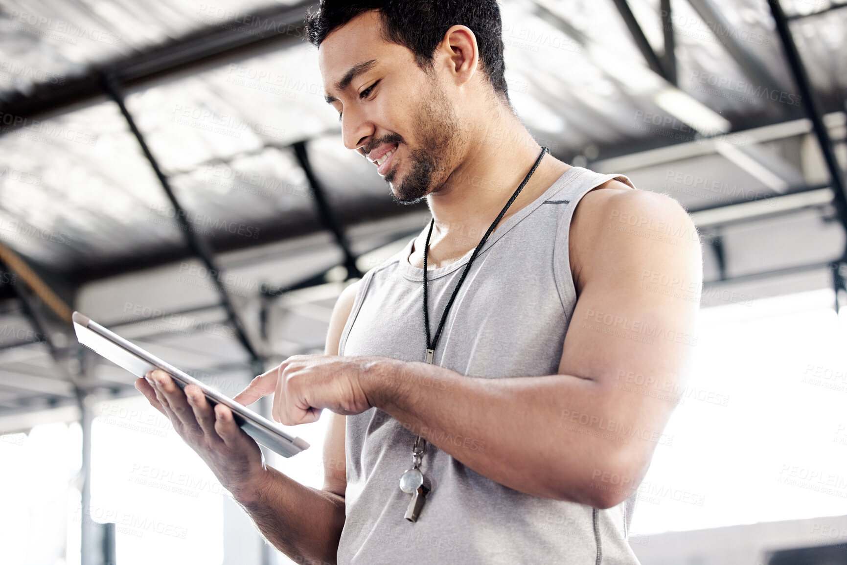 Buy stock photo Shot of a handsome young man using a digital tablet at the gym