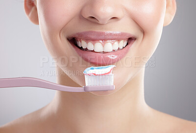 Buy stock photo Studio shot of an unrecognizable young woman brushing her teeth against a grey background