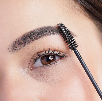 Buy stock photo Closeup portrait of an attractive young woman apllying eyebrow makeup in studio against a grey background