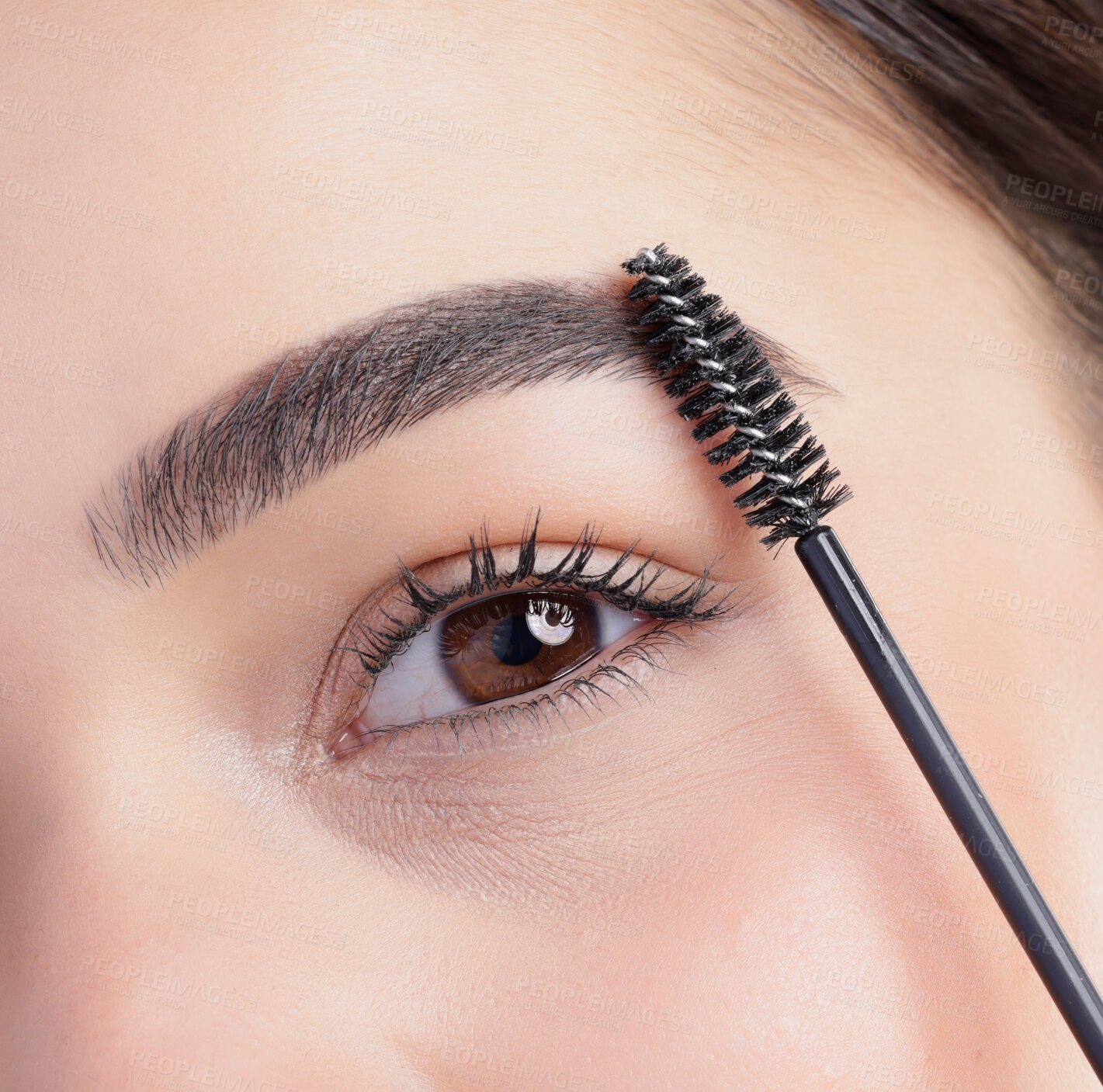 Buy stock photo Closeup portrait of an attractive young woman apllying eyebrow makeup in studio against a grey background