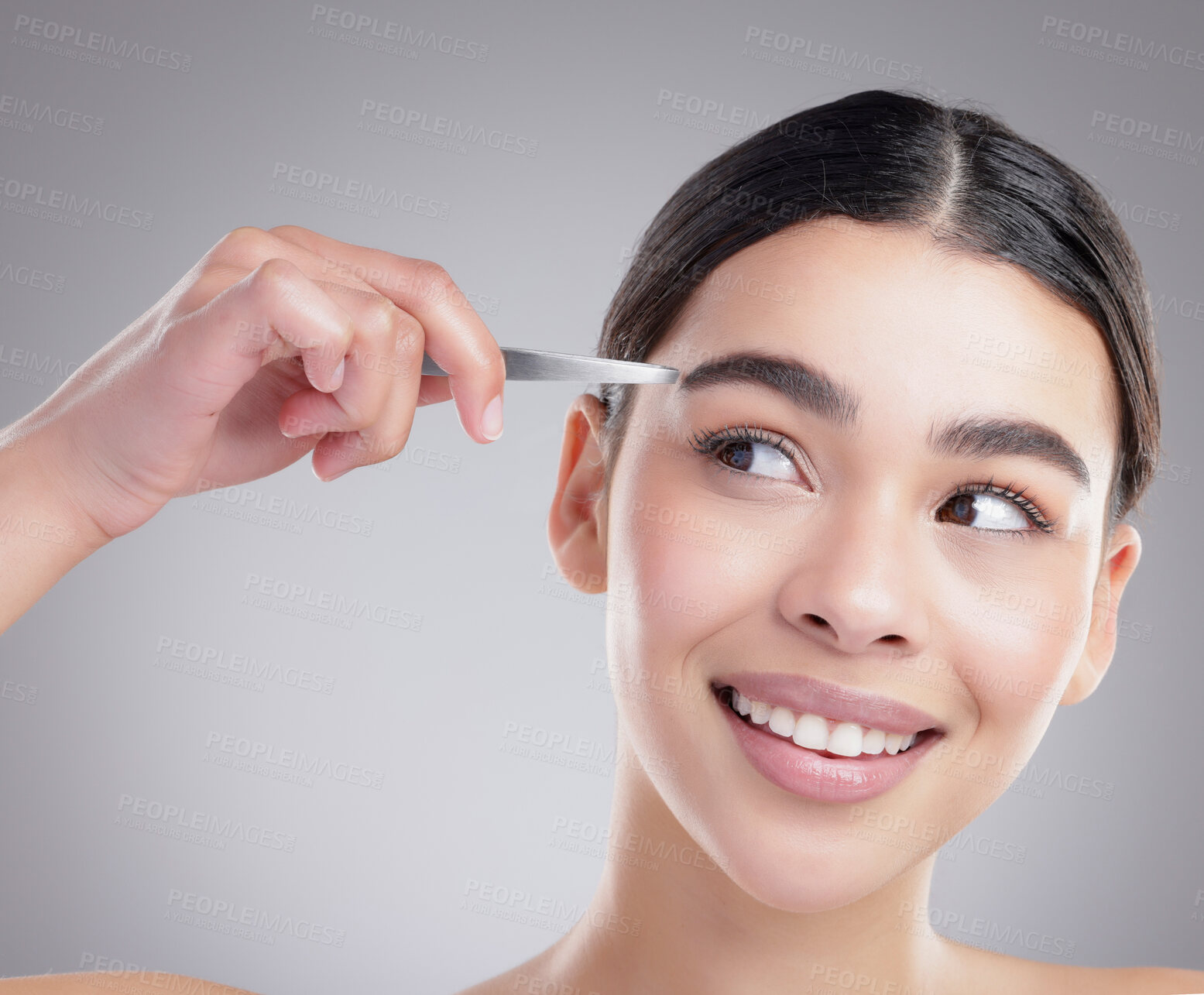 Buy stock photo Woman, smile and hand with tweezers in studio, facial hair removal routine and skincare. Self care, grooming and female model plucking her eyebrows for face epilation treatment by grey background