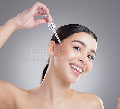 Buy stock photo Studio portrait of an attractive young woman applying facial serum against a grey background