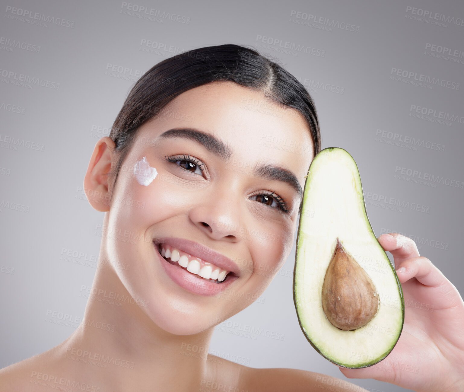 Buy stock photo Studio portrait of an attractive young woman posing with half an avo against a grey background