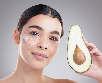Buy stock photo Studio portrait of an attractive young woman posing with half an avo against a grey background