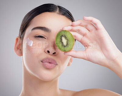 Buy stock photo Kiss, kiwi and lotion with portrait of woman in studio on gray background for diet, health or nutrition. Cream, fruit or pout and happy model with fresh produce for natural skincare or organic detox