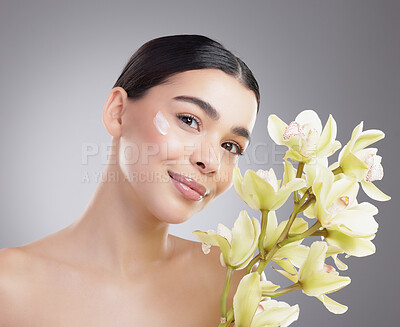 Buy stock photo Woman, portrait and flowers for cream in studio, sunscreen and eco friendly skincare on gray background. Female person, beauty and moisturizer for hydration, orchids and lotion treatment for cosmetic