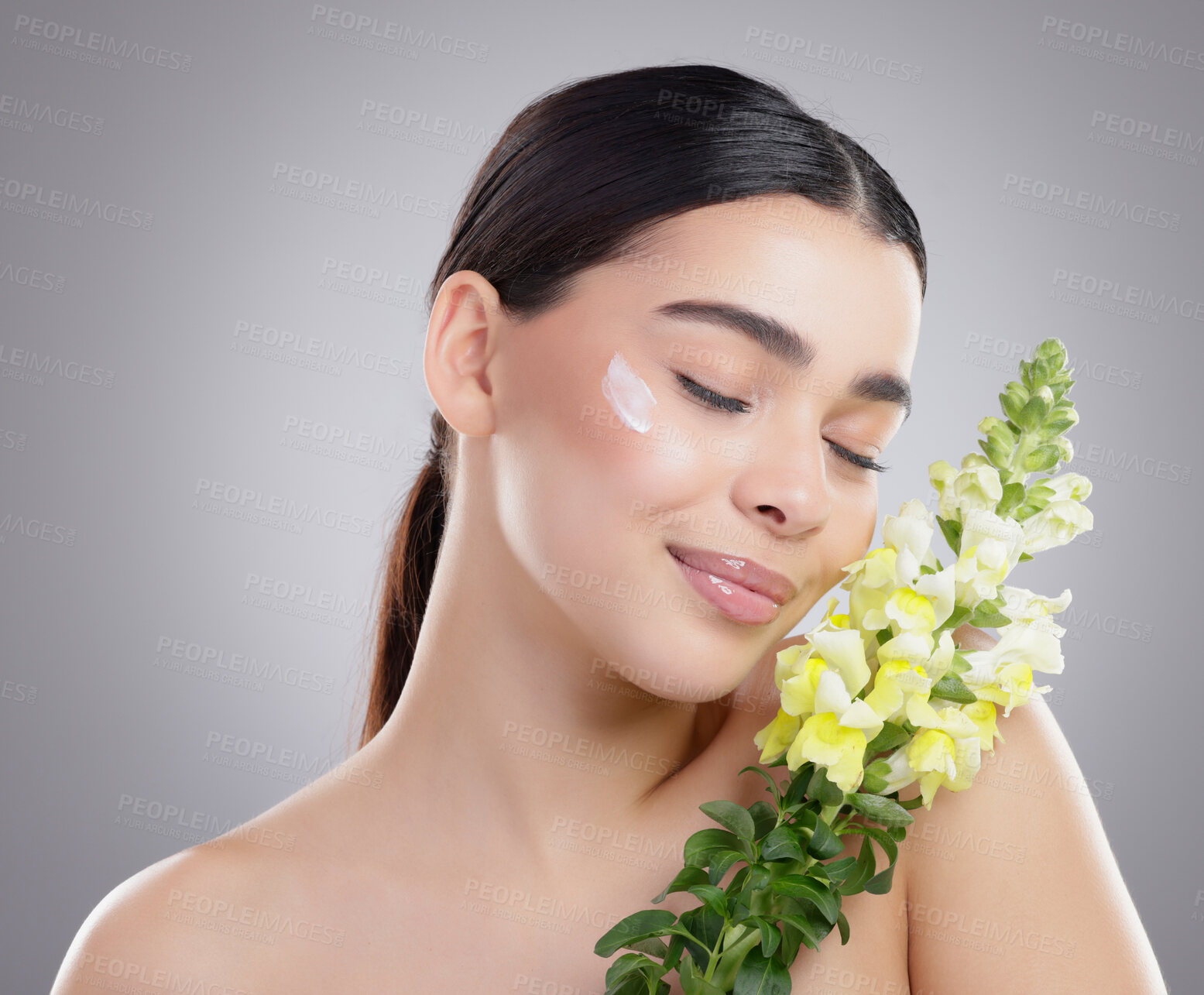 Buy stock photo Woman, beauty and flower for cream in studio, sunscreen and eco friendly skincare on gray background. Female person, sustainable and moisturizer for hydration, snapdragons and treatment for cosmetics