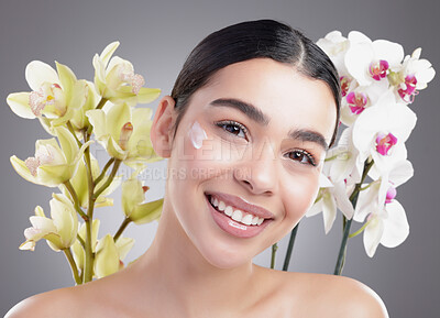Buy stock photo Studio portrait of an attractive young woman posing with two bunches of flowers against a grey background