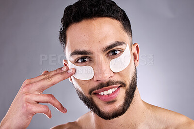 Buy stock photo Beauty, eye mask and smile with portrait of man in studio on gray background for facial or skincare. Aesthetic, face and wellness with happy model touching skin for dermatology, grooming or hydration