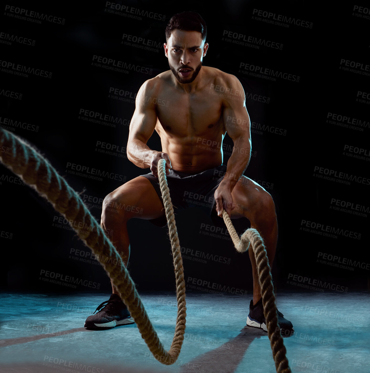 Buy stock photo Man, portrait and fitness with battle rope for workout, training or intense exercise on a black background. Active male person or young athlete with muscle for endurance, stamina or challenge at gym