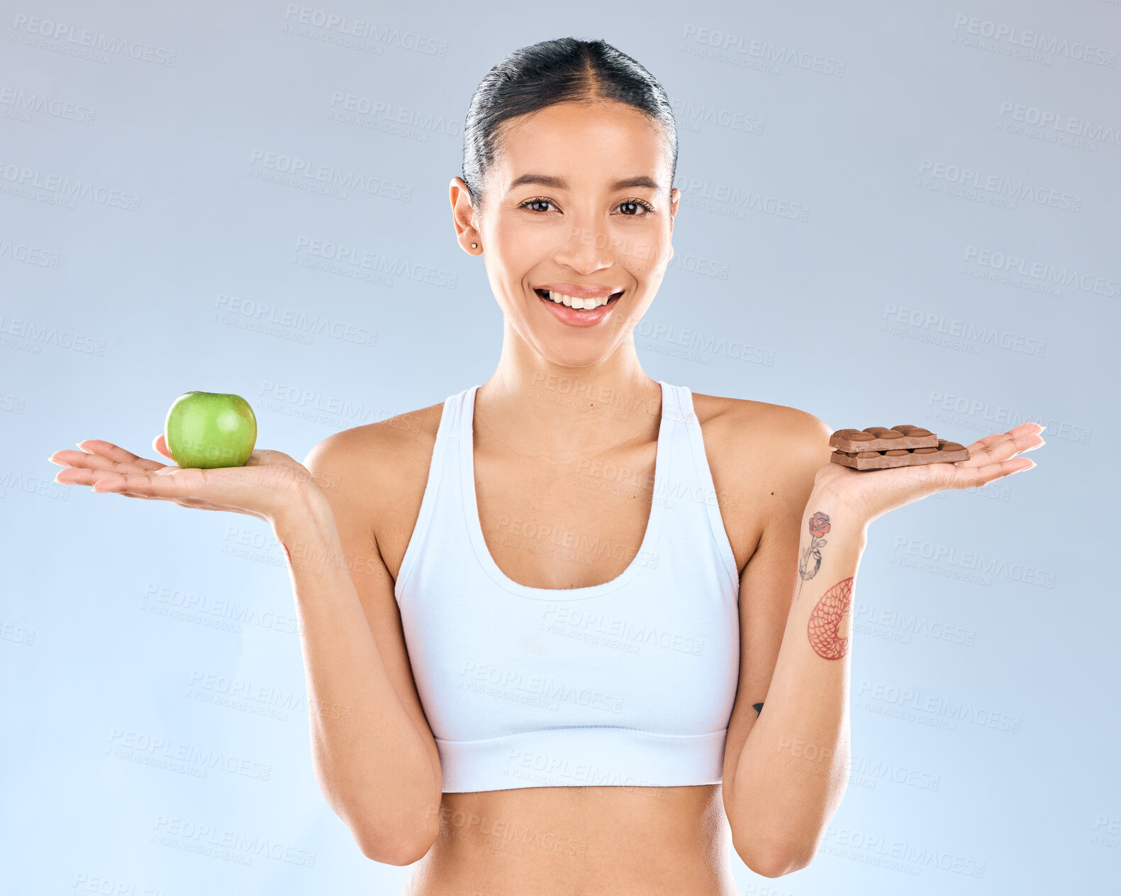 Buy stock photo Woman, portrait and choice with apple or chocolate for diet, decision or options on a blue studio background. Female person, fruit and candy for nutrition, dessert or balance for vitamin or calories