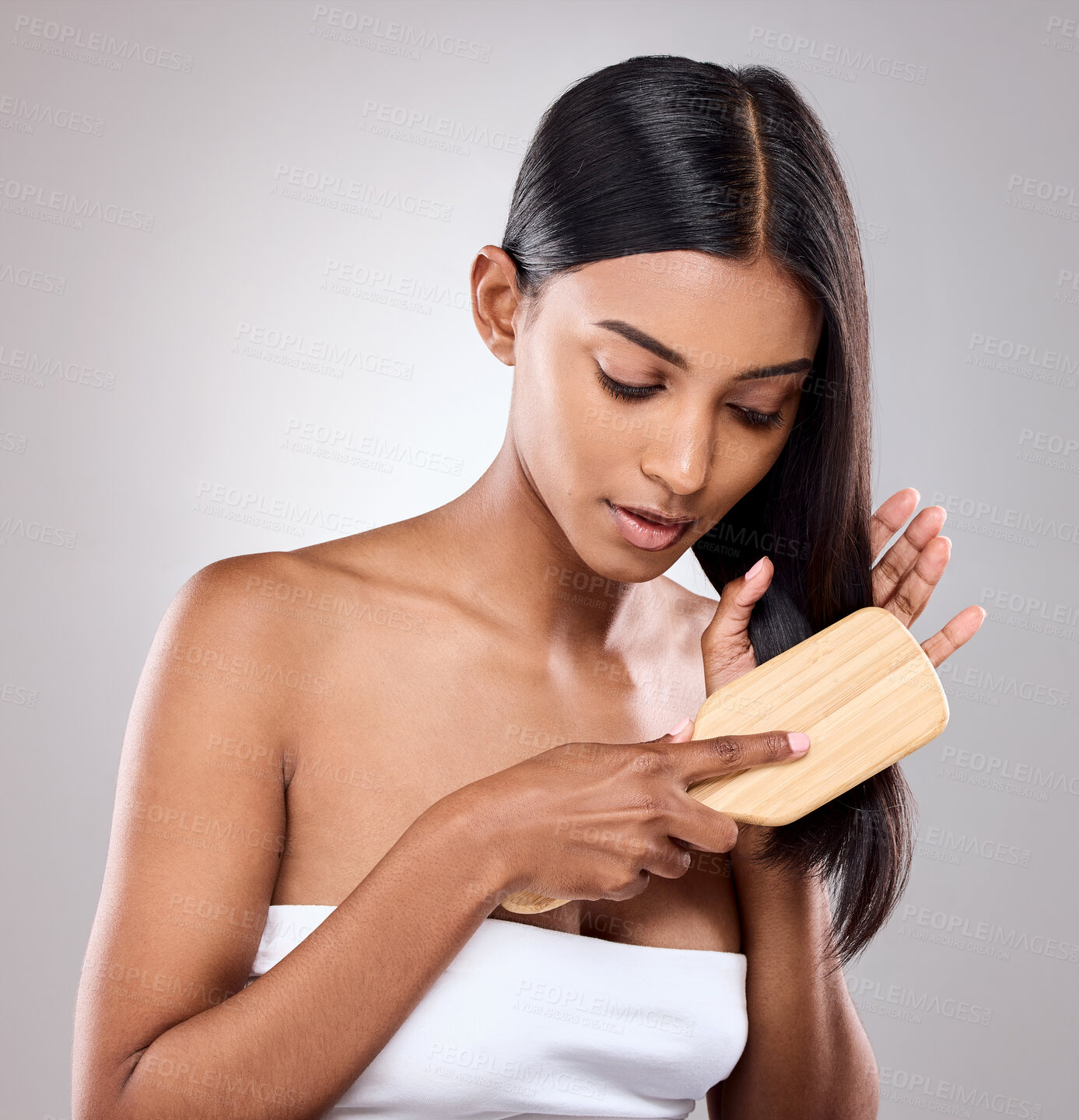 Buy stock photo Shot of an attractive young woman brushing her hair against a grey background