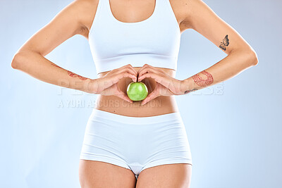 Buy stock photo Wellness, diet and hands with apple for slim body, self care and healthy stomach on white background studio. Fitness, exercise and heart of woman with fruit for vitamins, nutrition and weightloss