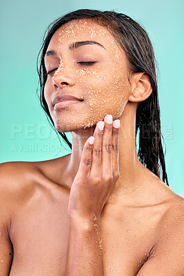 Buy stock photo Shot of a young woman washing her face with a product against a blue background