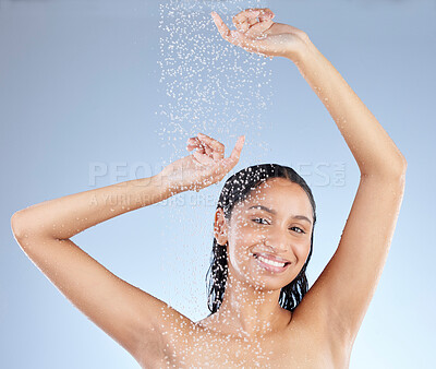 Buy stock photo Studio portrait of an attractive young woman taking a shower against a blue background