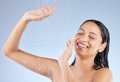 Buy stock photo Studio shot of an attractive young woman taking a shower against a blue background