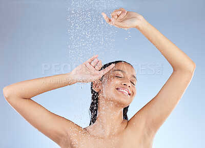 Buy stock photo Studio shot of an attractive young woman taking a shower against a blue background