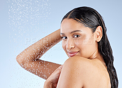 Buy stock photo Studio portrait of an attractive young woman taking a shower against a blue background