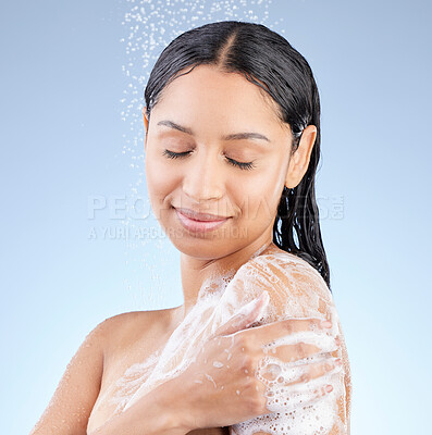 Buy stock photo Studio shot of an attractive young woman taking a shower against a blue background