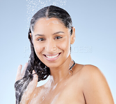 Buy stock photo Studio portrait of an attractive young woman taking a shower against a blue background