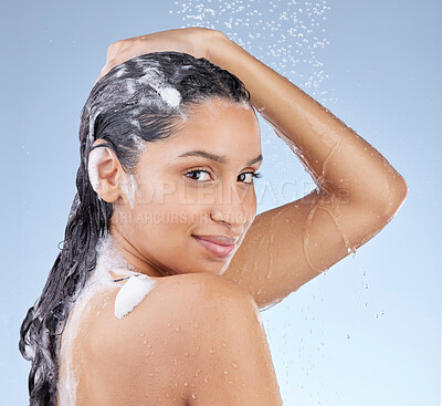 Buy stock photo Studio portrait of an attractive young woman taking a shower against a blue background