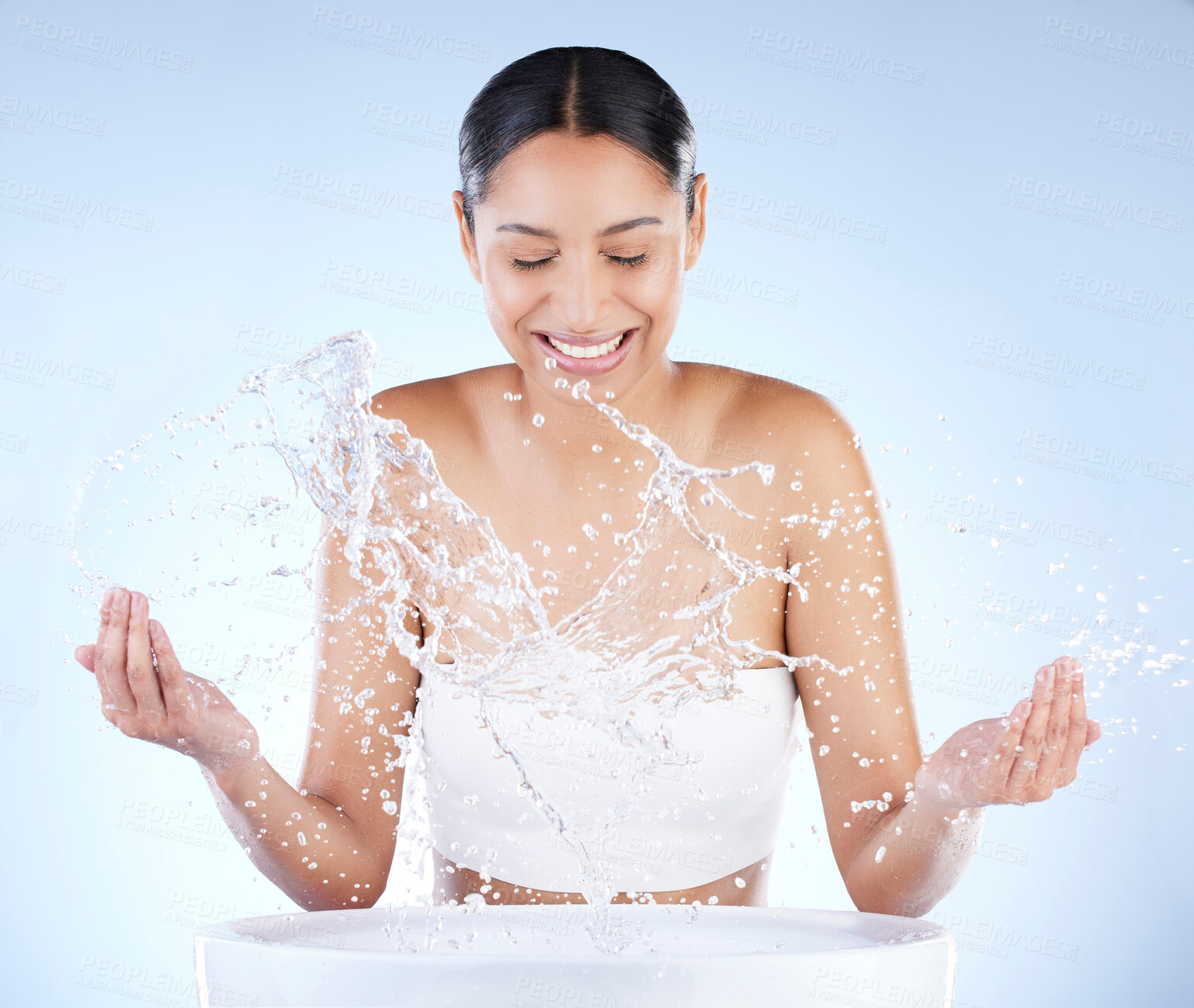 Buy stock photo Shot of a young woman washing herself against a blue background