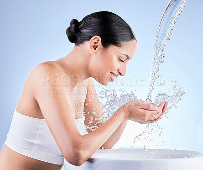 Buy stock photo Shot of a young woman washing herself against a blue background